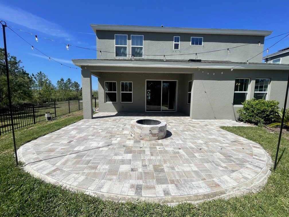 Completed backyard paver patio with a round fire pit in Tampa Bay