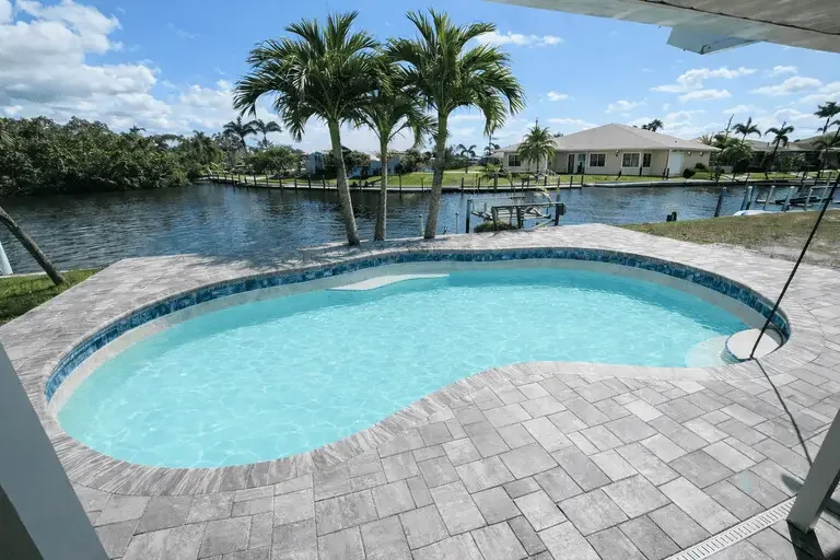 Completed travertine pool deck with canal-side pool and light stone surface in Tampa Bay