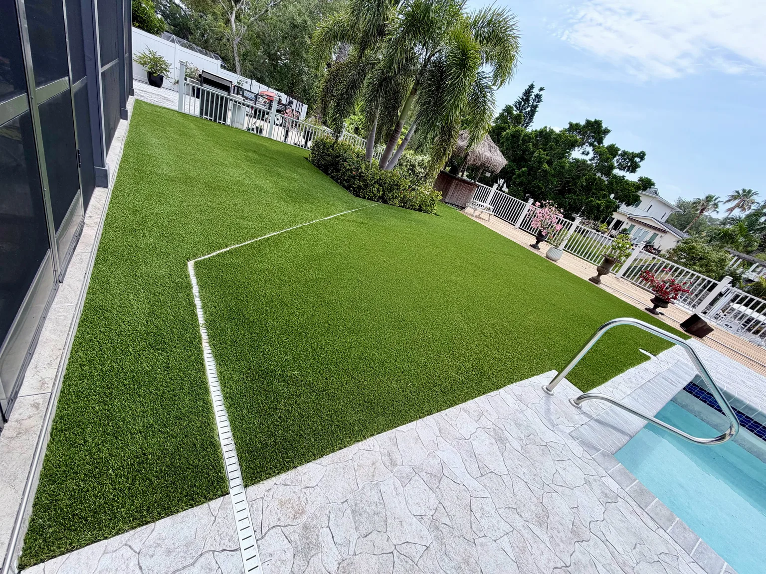 Completed artificial turf lawn beside a swimming pool and light pool deck