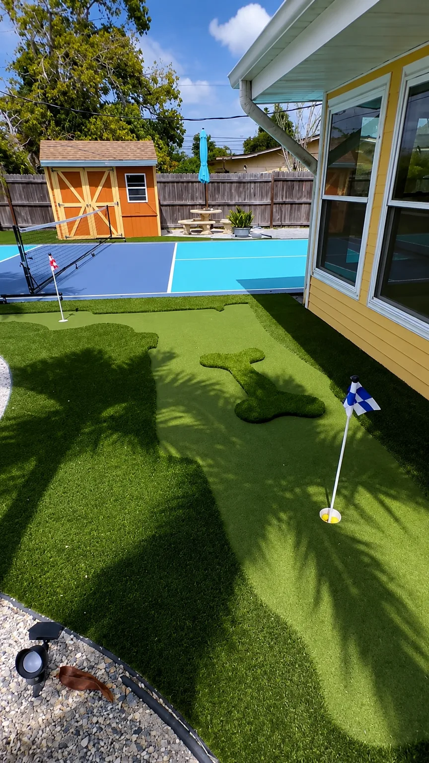 Completed residential putting green beside a screened patio, pool area, and backyard gazebo