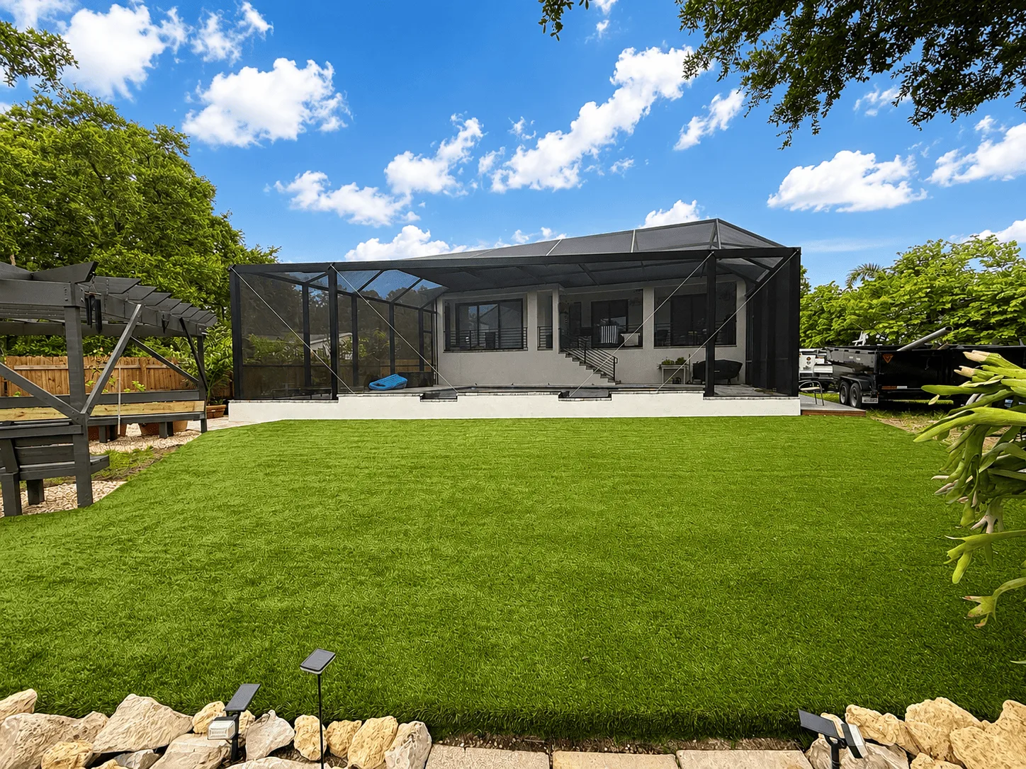 Finished green artificial turf backyard beside a screened pool enclosure in Tampa Bay