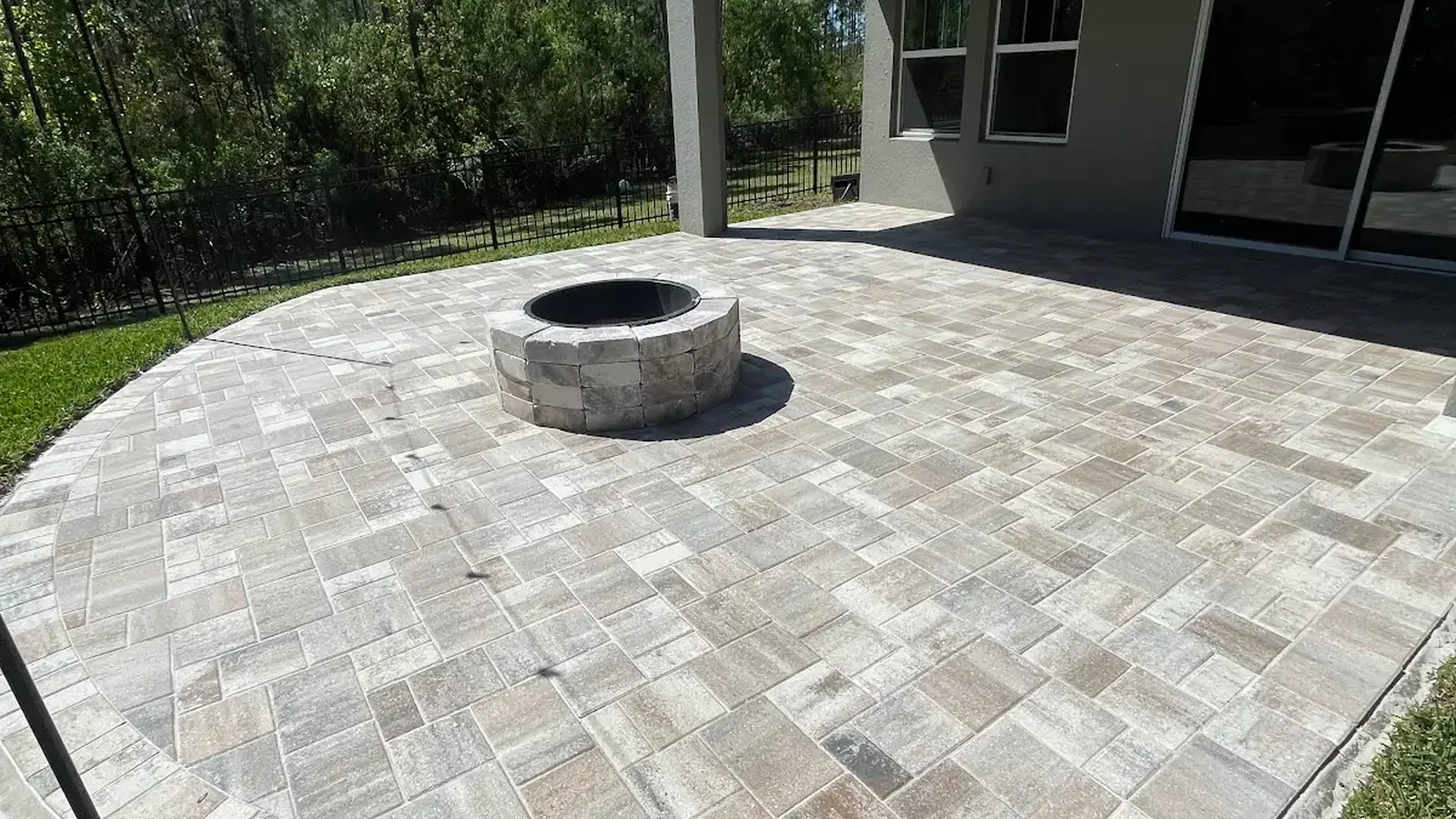 stone fire pit on a large paver patio in a Tampa Bay backyard