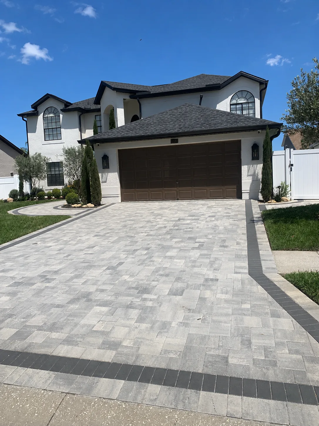 Completed modern gray paver driveway with a dark border leading to a two-car garage