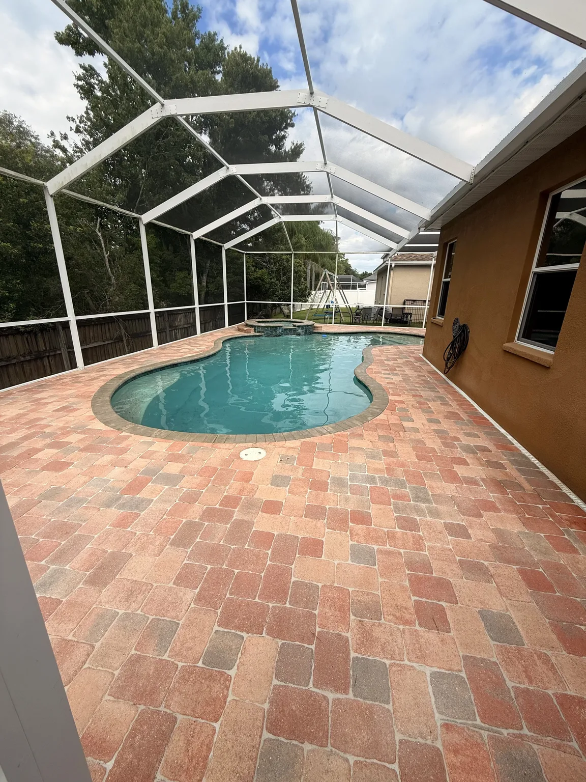 Refreshed paver pool deck after sealing inside a screened enclosure in Tampa Bay