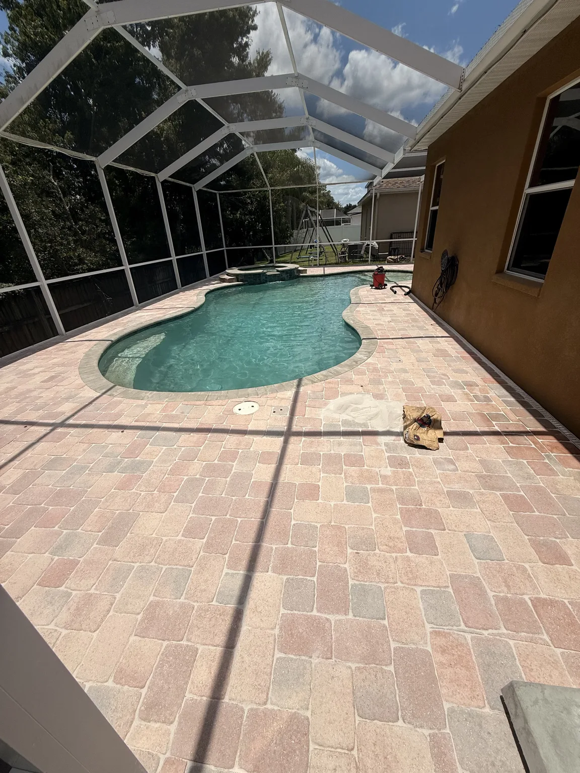 Paver pool deck before sealing inside a screened enclosure in Tampa Bay