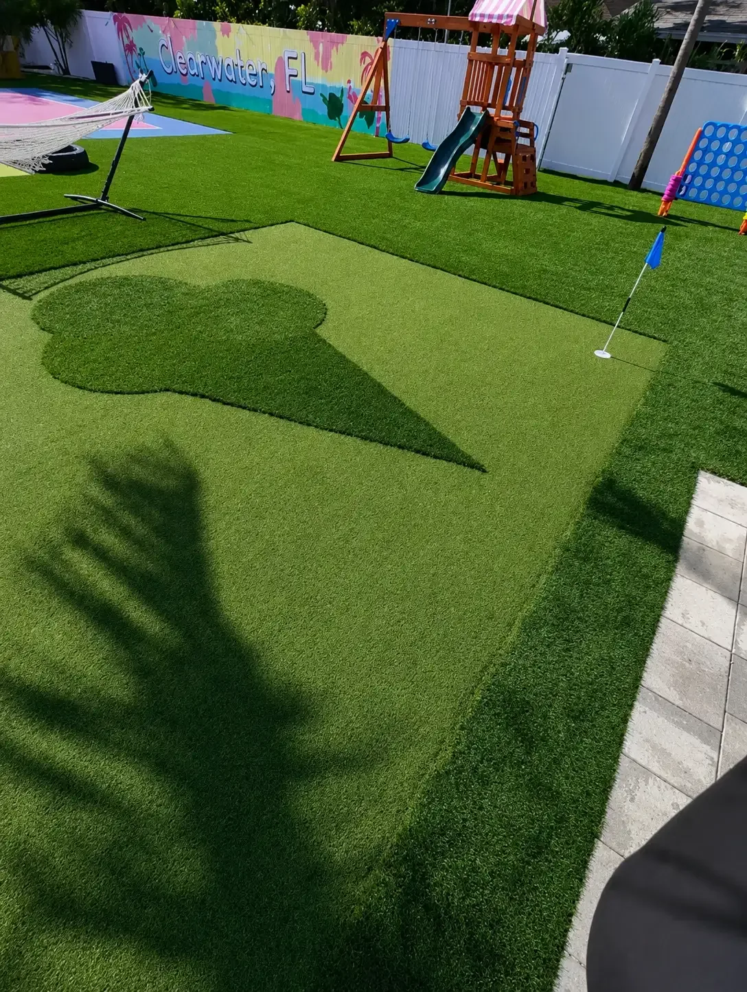 Completed artificial turf putting green with a backyard playset and recreation area in Tampa Bay