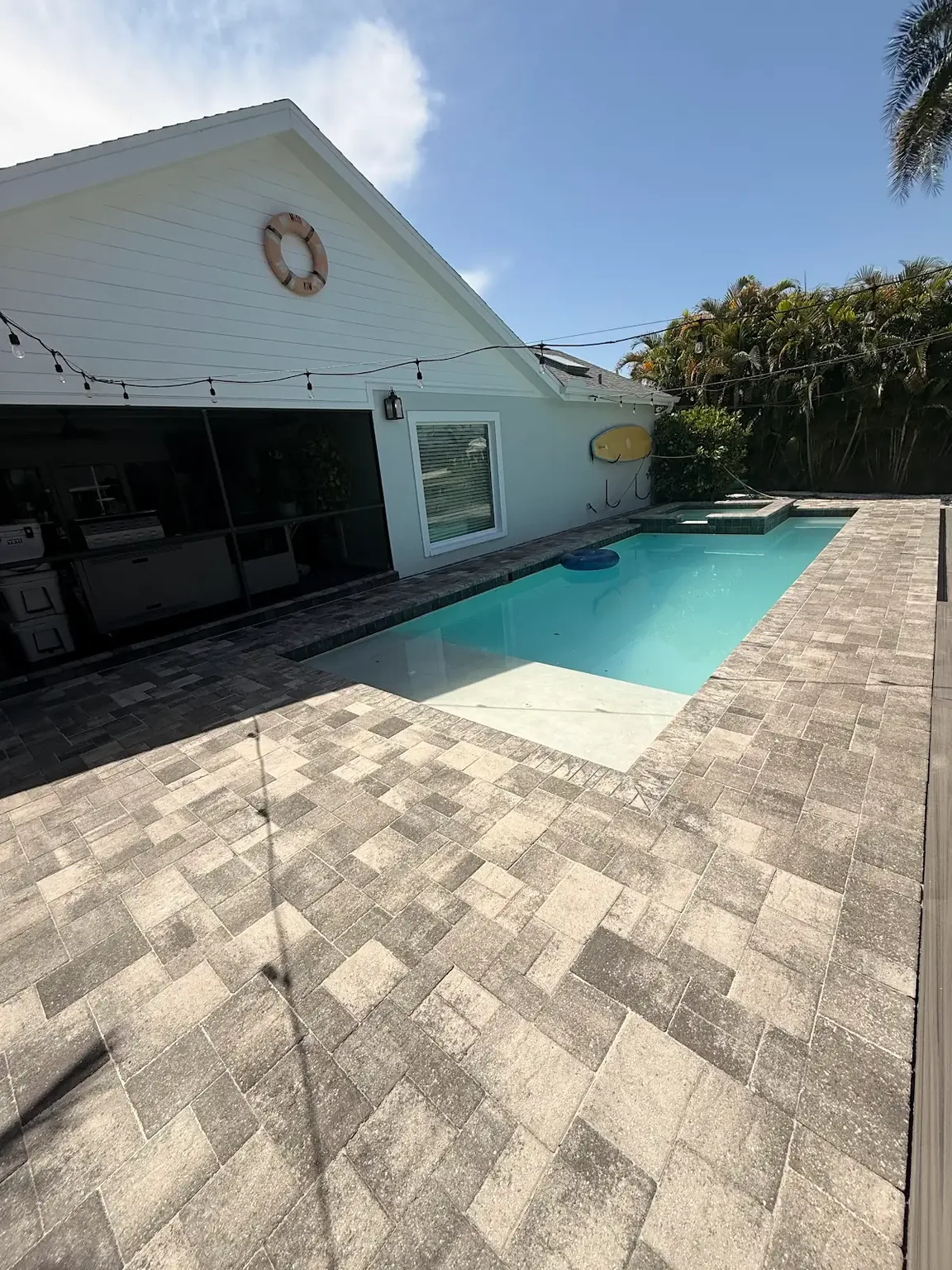 Alternate view of a completed gray paver pool deck surrounding a residential pool in Tampa Bay