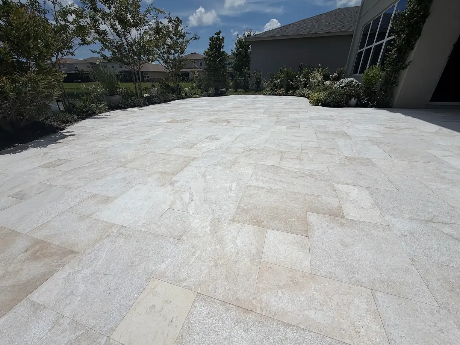 Wide view across a completed large light marble patio at a Tampa Bay residence