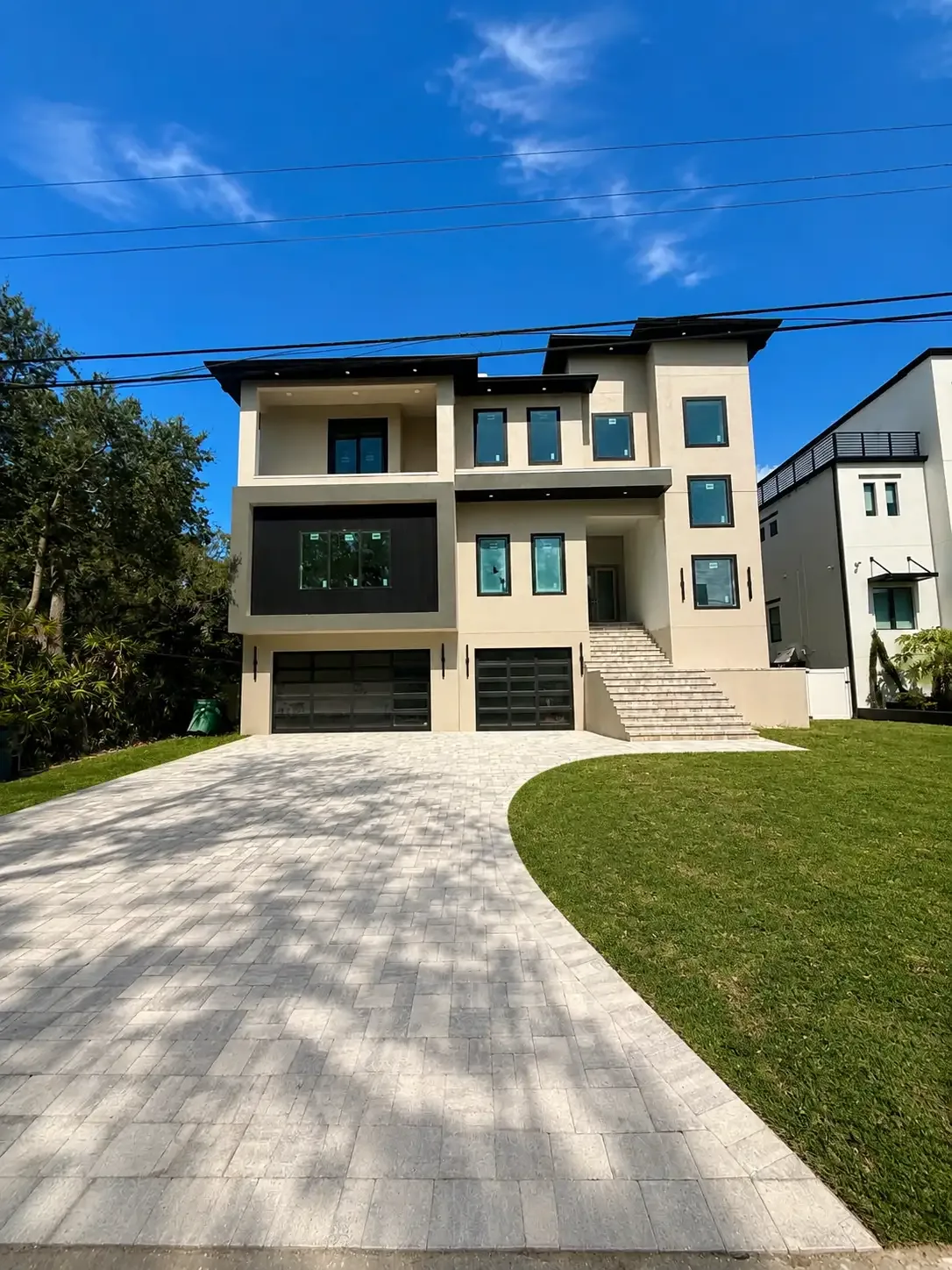Full view of a completed light gray paver driveway at a modern multi-story Tampa Bay home
