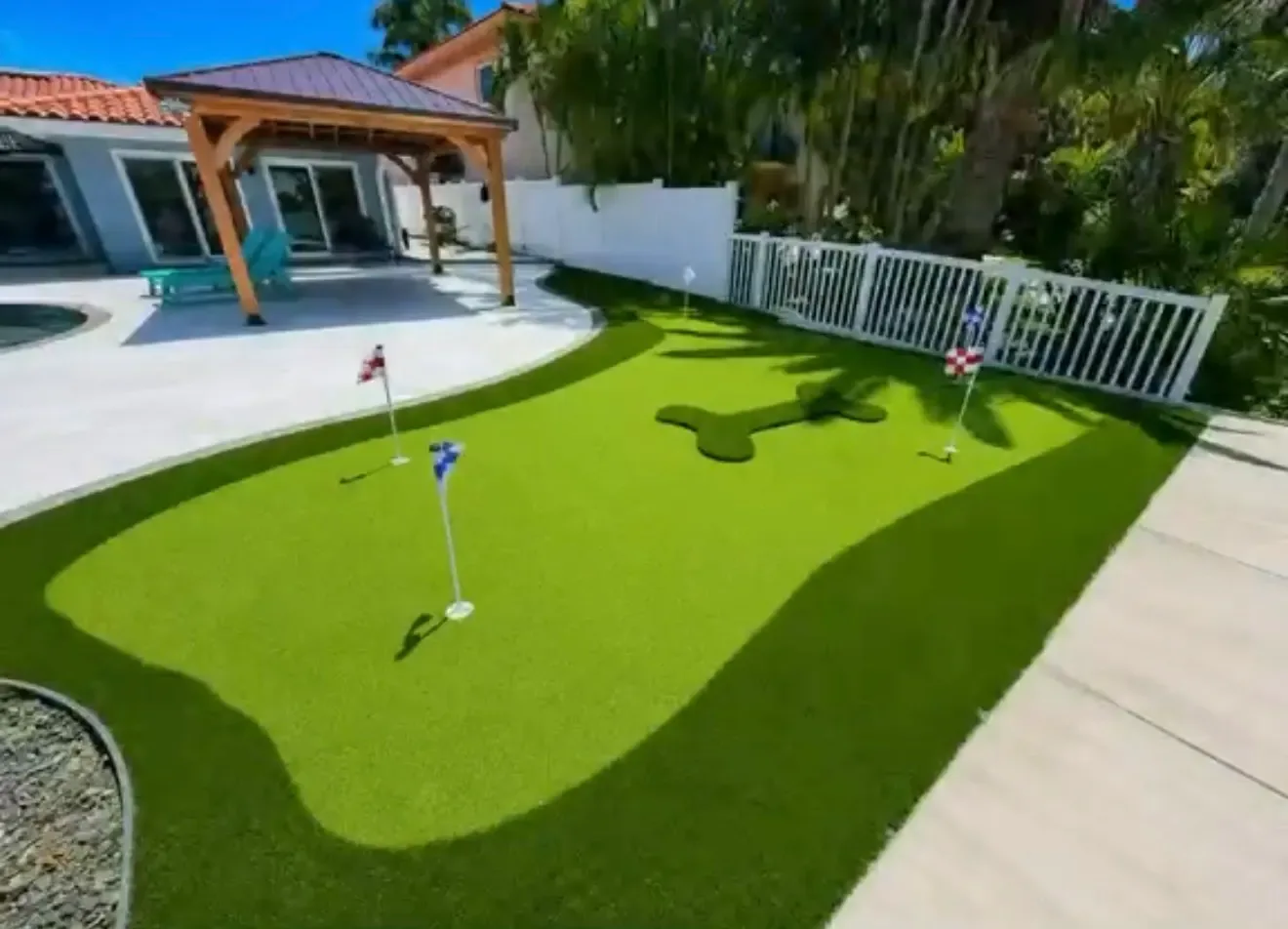 Completed artificial turf putting green beside a residential pool and covered patio in Tampa Bay