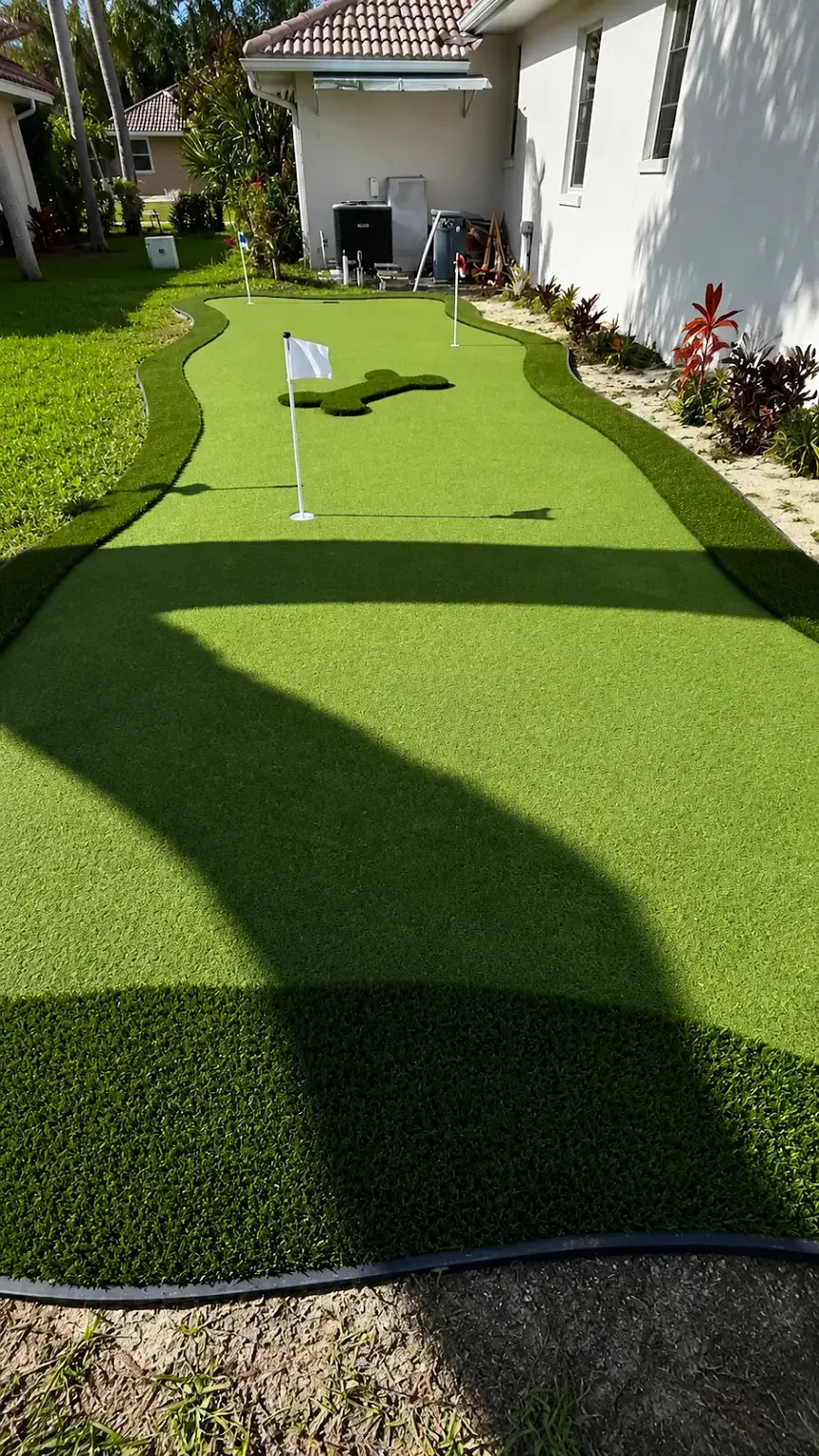 Long view of a completed side yard artificial turf putting green beside a home in Tampa Bay