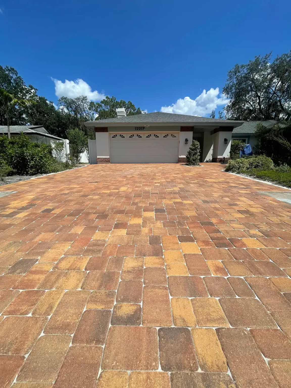 Completed warm tan and rust interlocking paver driveway leading to a residential garage in Tampa Bay