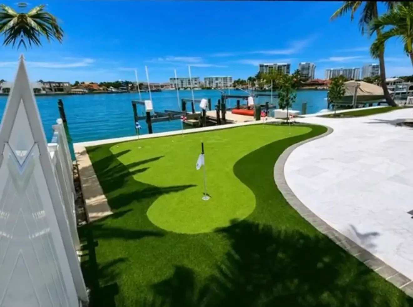 Completed waterfront artificial turf putting green beside a curved pool deck in Tampa Bay